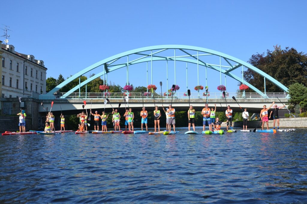 paddleboardisté pózující na řece v Turnově pod klenutým mostem. 12 Miles SUP Race